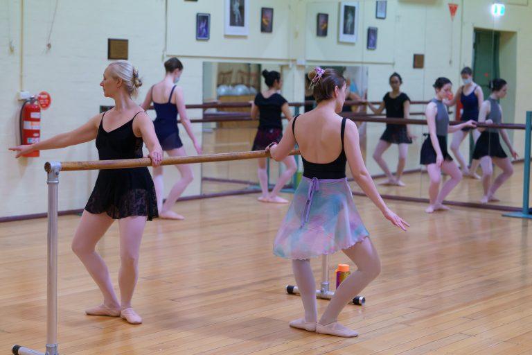 Adult Ballet students in class at barre